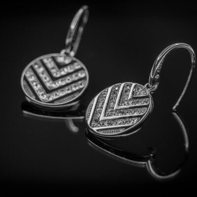 Close-up of luxurious diamond earrings with intricate design on a black background.