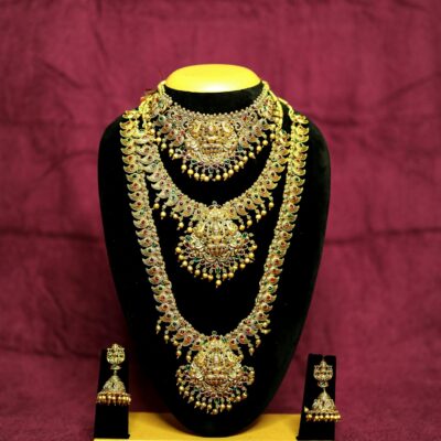 Stunning gold necklace with intricate design and matching earrings on black velvet stand.